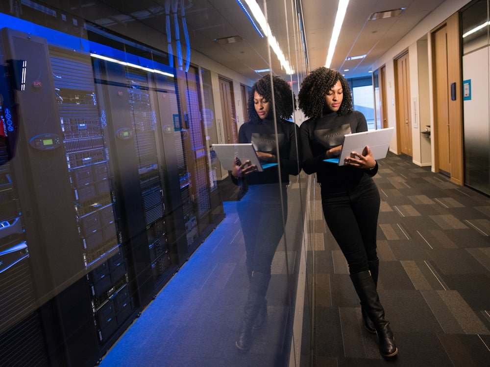 An IT professional with a laptop walking past a row of server racks