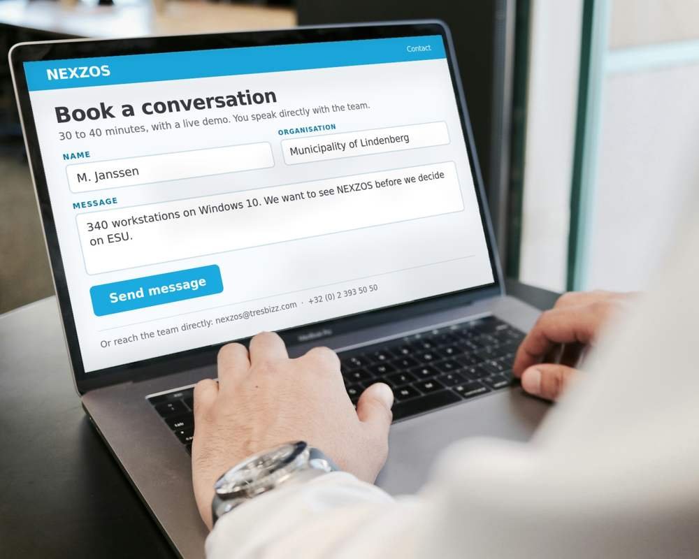 Hands on a laptop keyboard, the NEXZOS contact form filled in on the screen