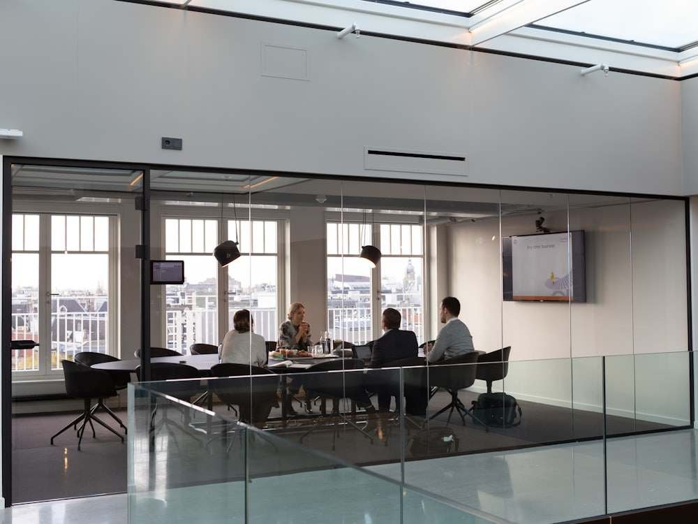 A glass-walled meeting room with people at a table