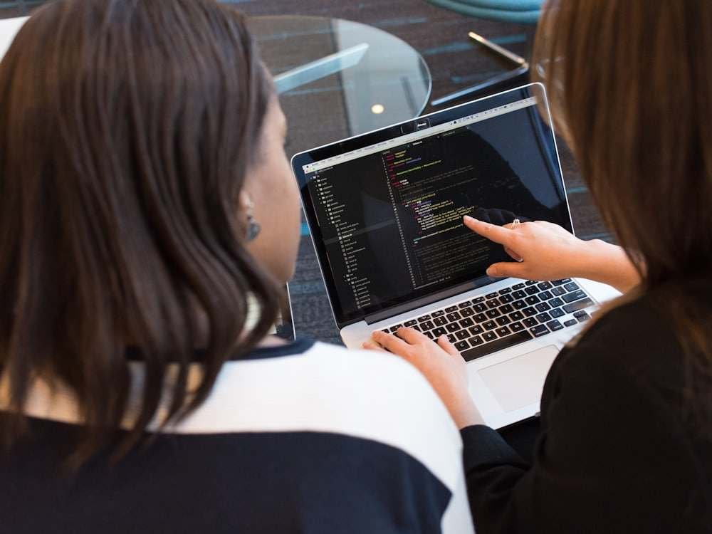 Two colleagues pointing at code on a laptop screen