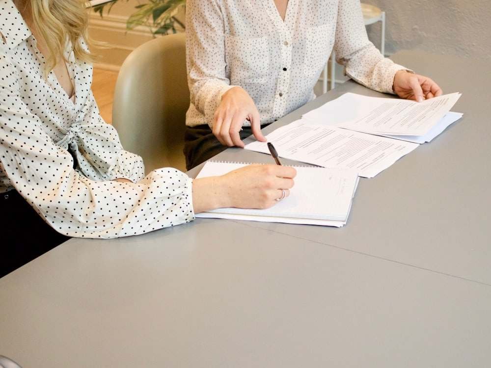 Two people going through a document at a desk, one signing