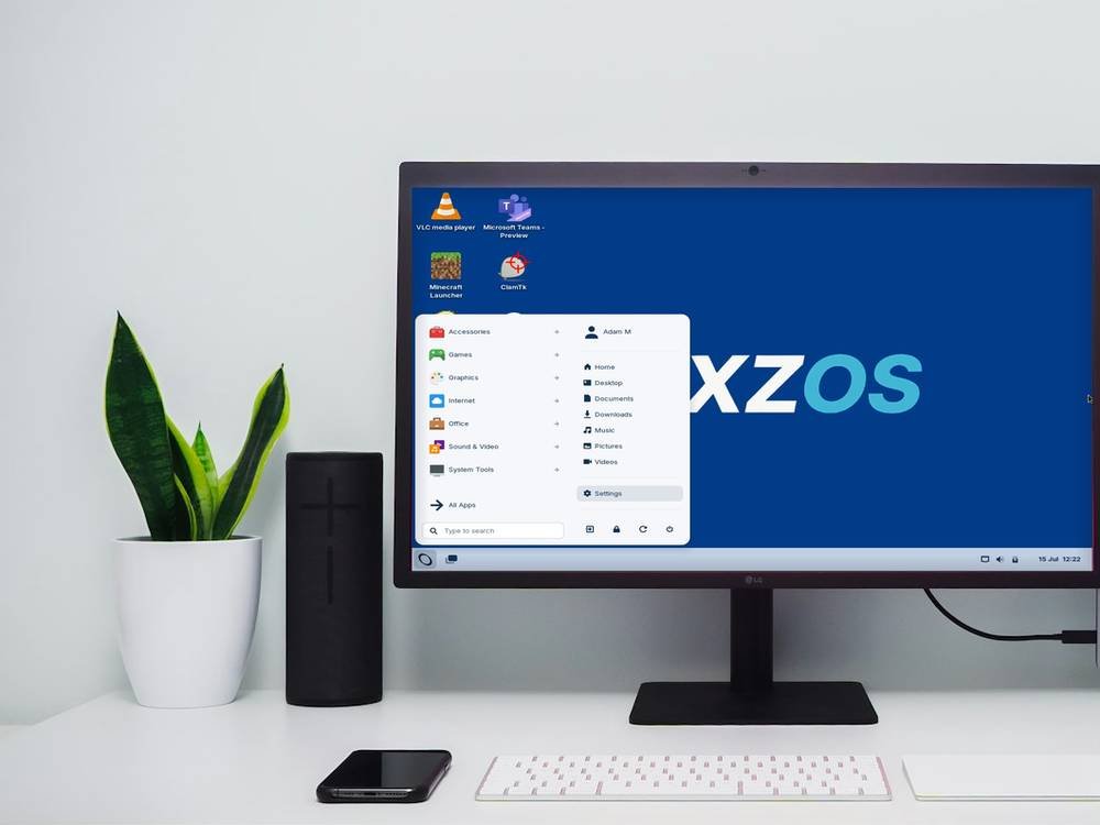 A desktop monitor on an office desk showing the NEXZOS desktop, with the application menu open