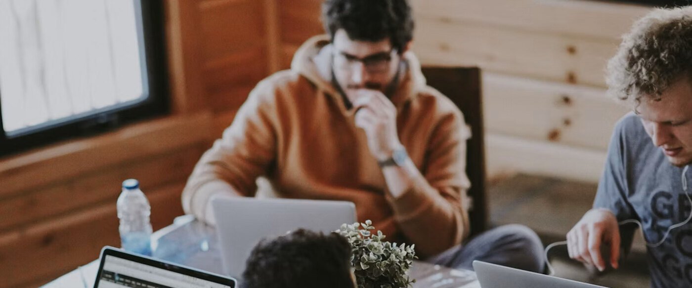 Three colleagues working together at one desk with laptops