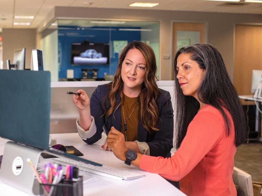 Two colleagues reviewing something on a monitor in a modern office